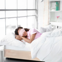 Woman in a pink sleep mask peacefully resting in a cozy bed, promoting relaxation and self-care.